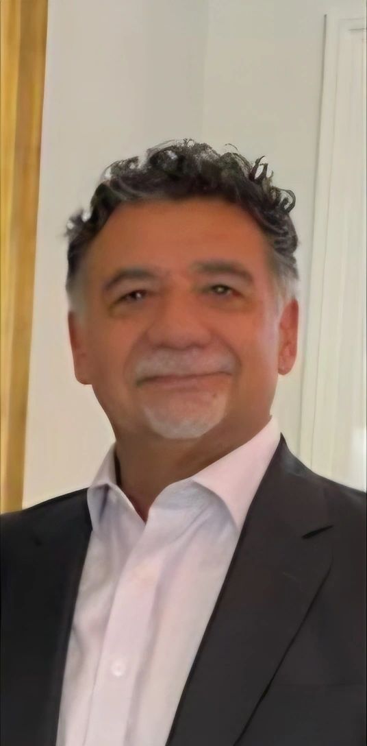 Man in a suit smiling warmly indoors.